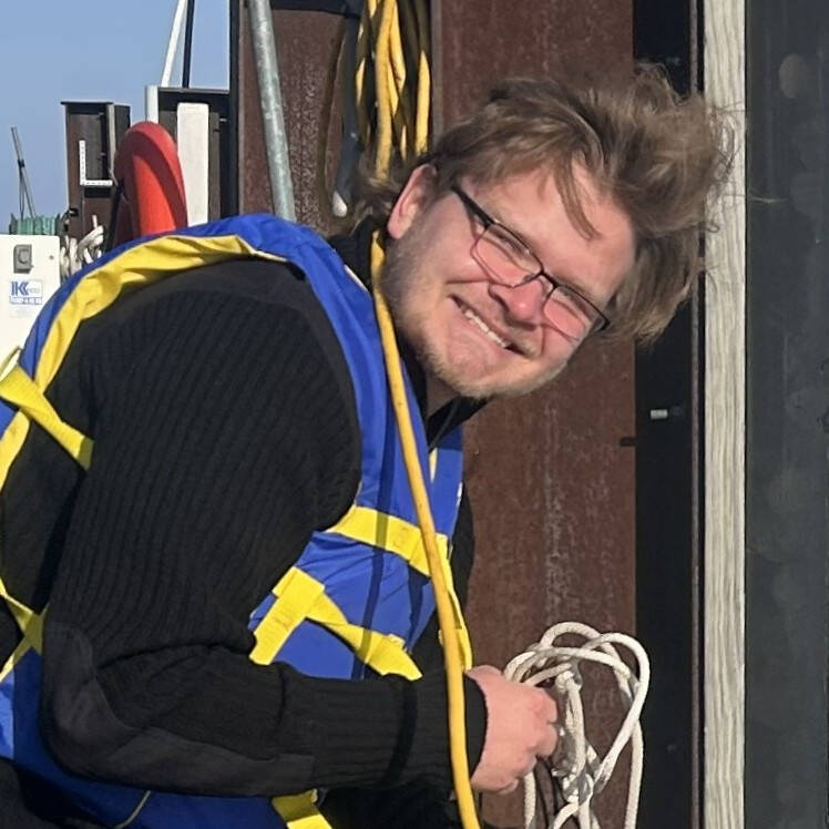 Andrei Skelley lowers sampling gear on a rope into the water at AWRI's dock.
